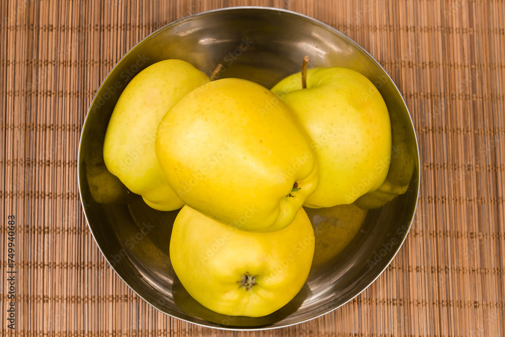 Yellow apples in metal bowl on table mat, top view Yellow apples in metal bowl on table mat, top view
