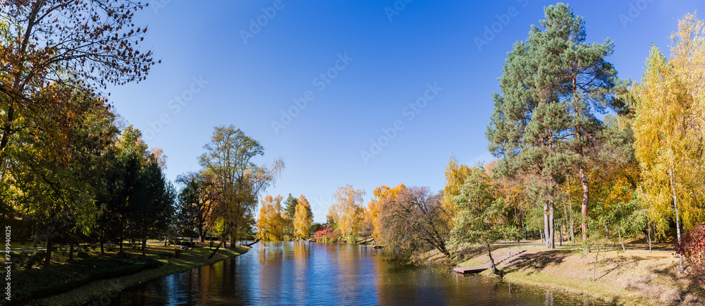 Scenic lake with different trees on banks in autumn park
