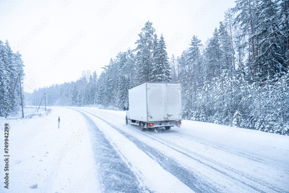 Car on the road in winter forest. Snowfall in Finland.