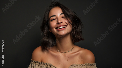 A gorgeous young lady with a lob haircut, wearing an off-the-shoulder shirt and delicate gold jewelry, radiantly confident against a backdrop of matte black photo