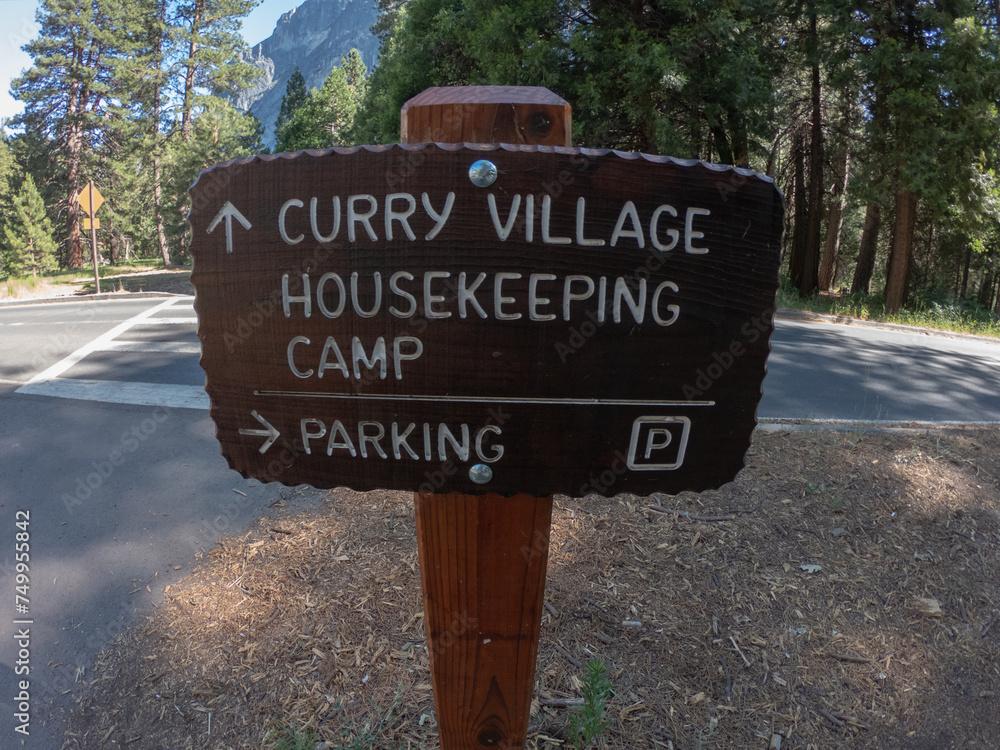 Wooden sign with arrow directions to Curry Village Housekeeping Camp and Parking, Yosemite National Park, California, USA.