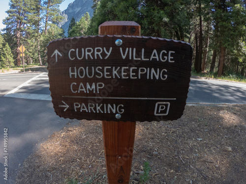 Wooden sign with arrow directions to Curry Village Housekeeping Camp and Parking, Yosemite National Park, California, USA.