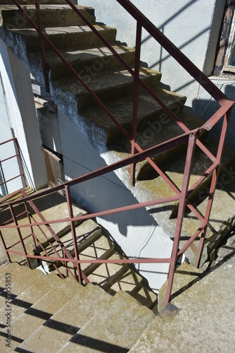 Emergency fire concrete staircase with metal handrails in the sunlight