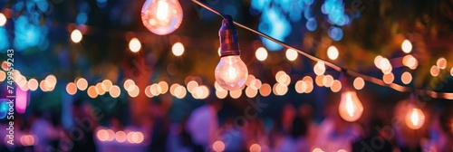 Festive outdoor lights decorating evening event - Beautiful outdoor string lights with glowing bulbs against a twilight sky create a festive and cozy atmosphere for an event or party photo