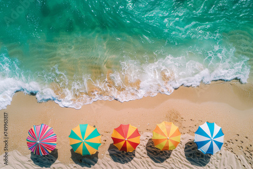 Aerial view of a tropical beach lined with colorful umbrellas, epitomizing leisure and summer vibes.