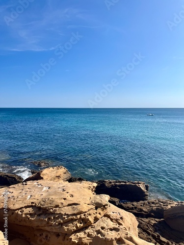 Beautiful azure ocean horizon, rocky coast, clear blue sky