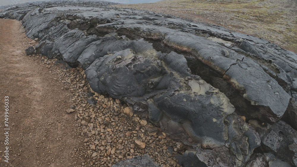 View of cracked lava crust or ingenious rock and steam cooled down from the 2021 eruption of Fagradalsfjall volcano in Geldingadalir Valley on Reykjanes Peninsula in Iceland.