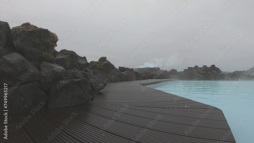 The Blue Lagoon geothermal spa Iceland, in a lava field near Grindavík on Reykjanes Peninsula. Water's milky blue shade is due to its high silica content. Woman relaxes and enjoy of spa in hot spring.