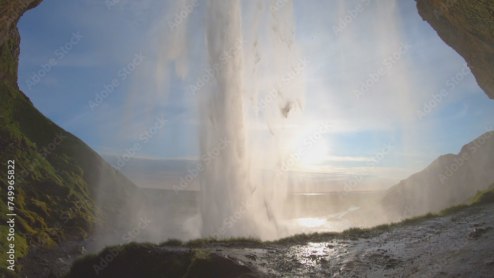 The Seljalandsfoss waterfall on the south coast of Iceland bathed in the otherworldly light of the midnight sun. The waterfall drops 60 meters and is part of the Seljalands River.