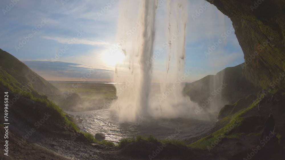 The Seljalandsfoss waterfall on the south coast of Iceland bathed in the otherworldly light of the midnight sun. The waterfall drops 60 meters and is part of the Seljalands River.