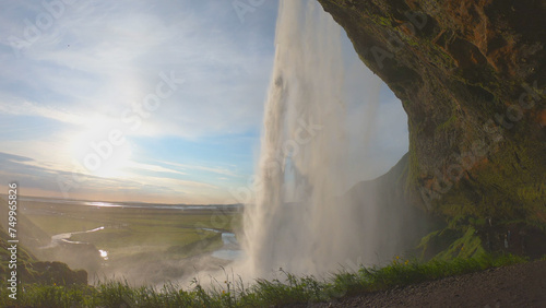 The Seljalandsfoss waterfall on the south coast of Iceland bathed in the otherworldly light of the midnight sun. The waterfall drops 60 meters and is part of the Seljalands River.