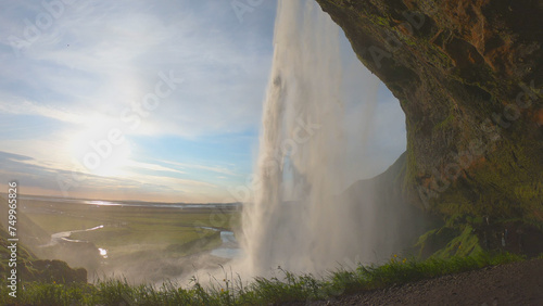 Obraz na płótnie The Seljalandsfoss waterfall on the south coast of Iceland bathed in the otherworldly light of the midnight sun. The waterfall drops 60 meters and is part of the Seljalands River. w salonie