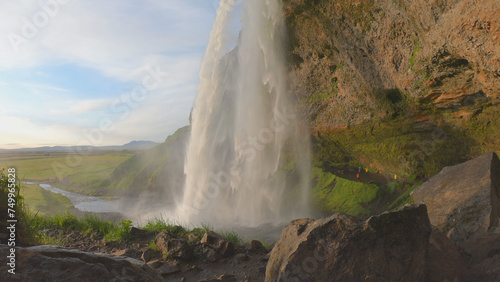 The Seljalandsfoss waterfall on the south coast of Iceland bathed in the otherworldly light of the midnight sun. The waterfall drops 60 meters and is part of the Seljalands River.