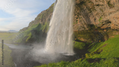 The Seljalandsfoss waterfall on the south coast of Iceland bathed in the otherworldly light of the midnight sun. The waterfall drops 60 meters and is part of the Seljalands River.