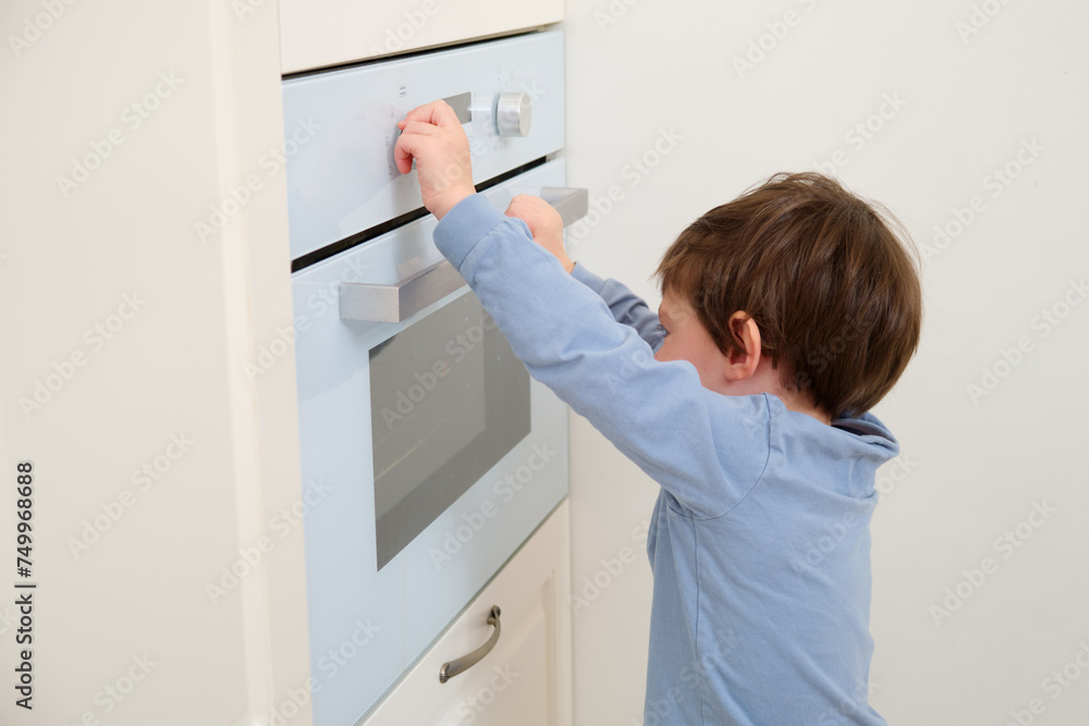 Child opening the oven in the kitchen at home. Focus on hand. Kid aged two (two year old)