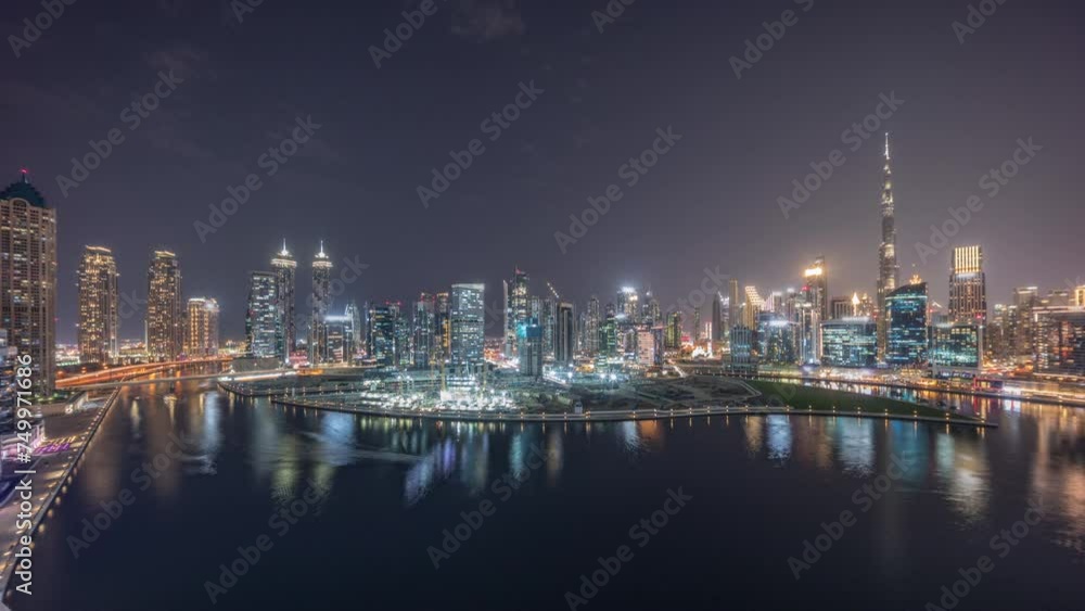 Aerial panorama of Dubai Business Bay and Downtown with the various skyscrapers and towers along waterfront on canal day to night transition timelapse. Construction site with cranes after sunset Aerial panorama of Dubai Business Bay and Downtown with the various skyscrapers and towers along waterfront on canal day to night transition timelapse. Construction site with cranes after sunset