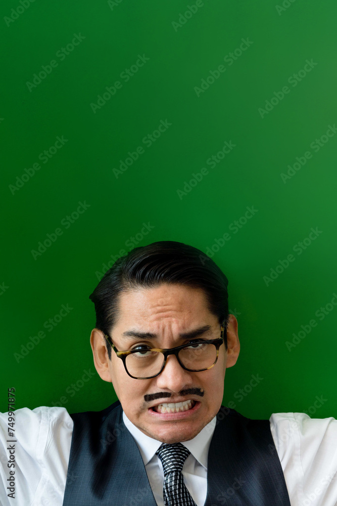 Eccentric Latin man wearing glasses making facial expression looking at camera on the green background Eccentric Latin man wearing glasses making facial expression looking at camera on the green background