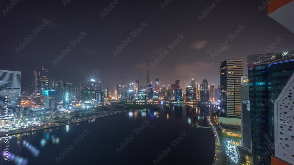Aerial panoramic view to Dubai Business Bay and Downtown with the various skyscrapers and towers along waterfront on canal night timelapse during all night. Construction site with cranes Aerial panoramic view to Dubai Business Bay and Downtown with the various skyscrapers and towers along waterfront on canal night timelapse during all night. Construction site with cranes