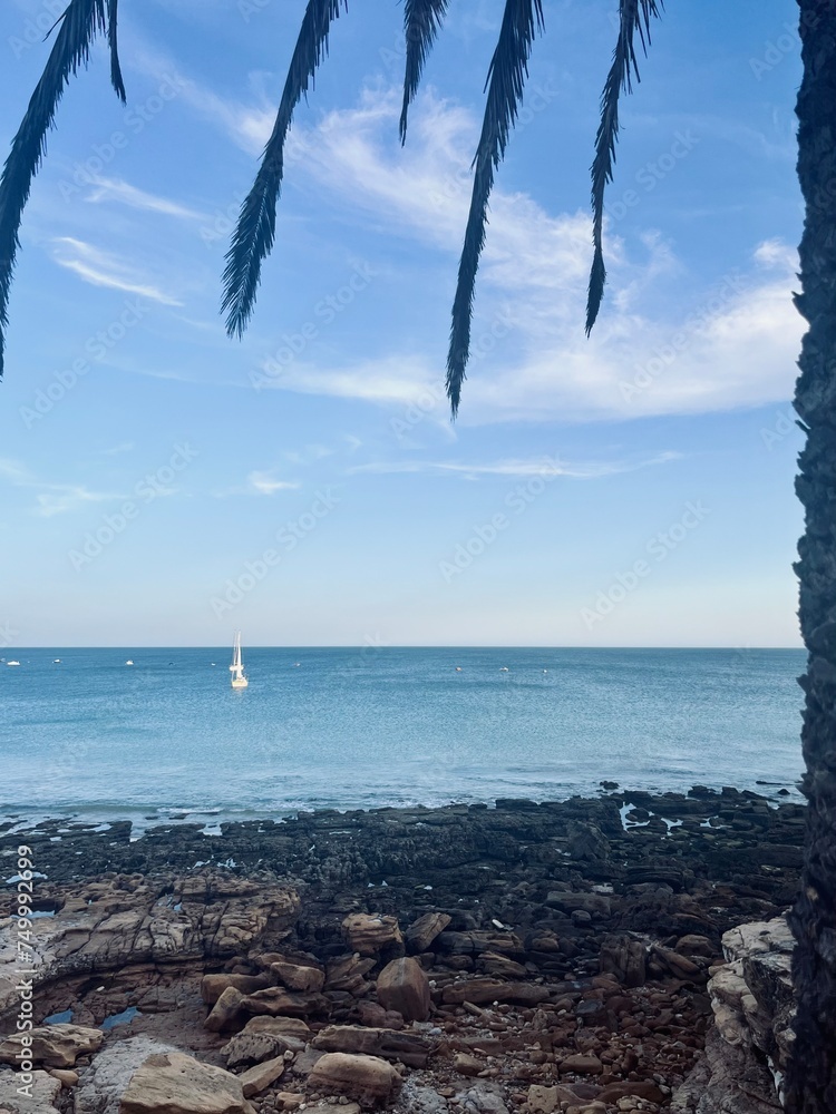White sail boats at the ocean, blue ocean horizon, rocky coast White sail boats at the ocean, blue ocean horizon, rocky coast
