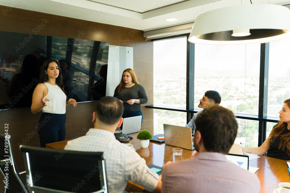 Couple of businesswomen in casual clothing giving a presentation to some clients Couple of businesswomen in casual clothing giving a presentation to some clients