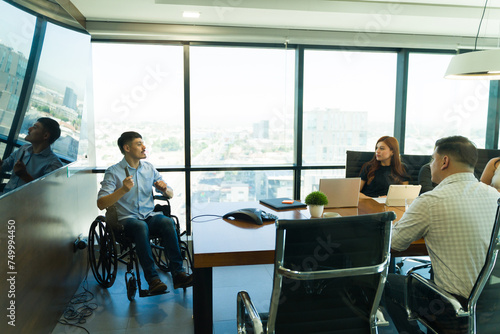 Disabled man in a wheelchair speaking to a group of people in a meeting room