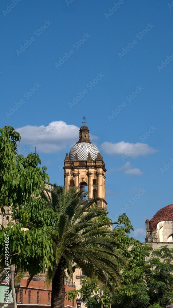 Tiled bell tower with trees below at the Church and Convent of Santo Domingo de Guzman in Oaxaca, Mexico