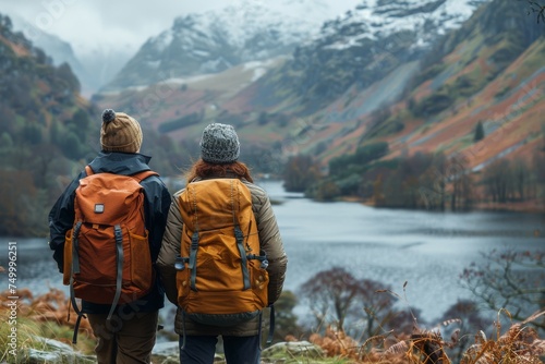 Pair of travelers with backpacks gazing at a vast mountain range in the autumn season