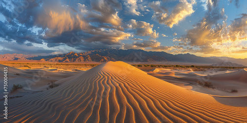 Ripples on sand dunes with dramatic clouds at sunset, mountains in the backdrop