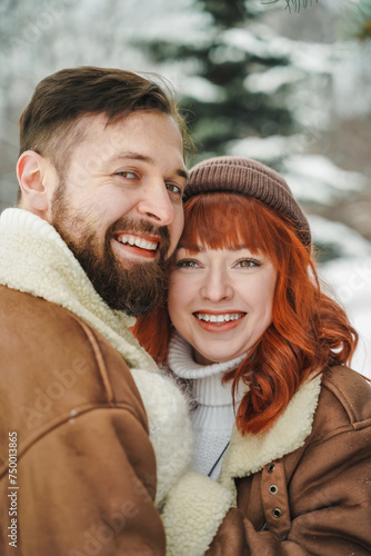 Love romantic couple lovestory. Brutal bearded man, bright red-haired girl woman in winter park. Romantic date, kissing, hugging. Walking, having fun. Stylish clothes, red sheepskin coat, jacket, hat