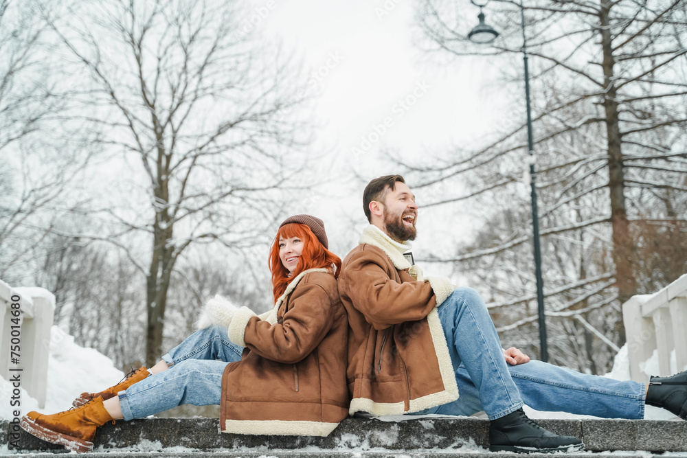 Obraz premium Love romantic couple lovestory. Brutal bearded man, bright red-haired girl woman in winter park. Romantic date, kissing, hugging. Walking, having fun. Stylish clothes, red sheepskin coat, jacket, hat
