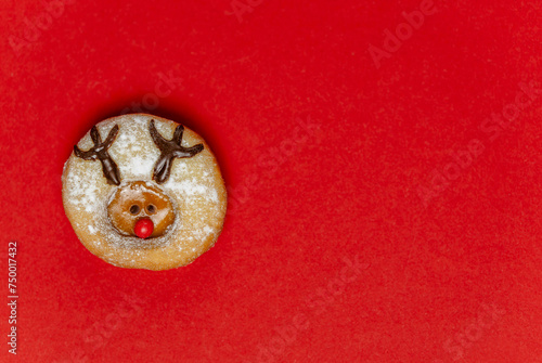Runder Keks mit einem Rentiergesicht auf rotem Hintergrund, auf der rechten Seite freier Platz, horizontal,  photo