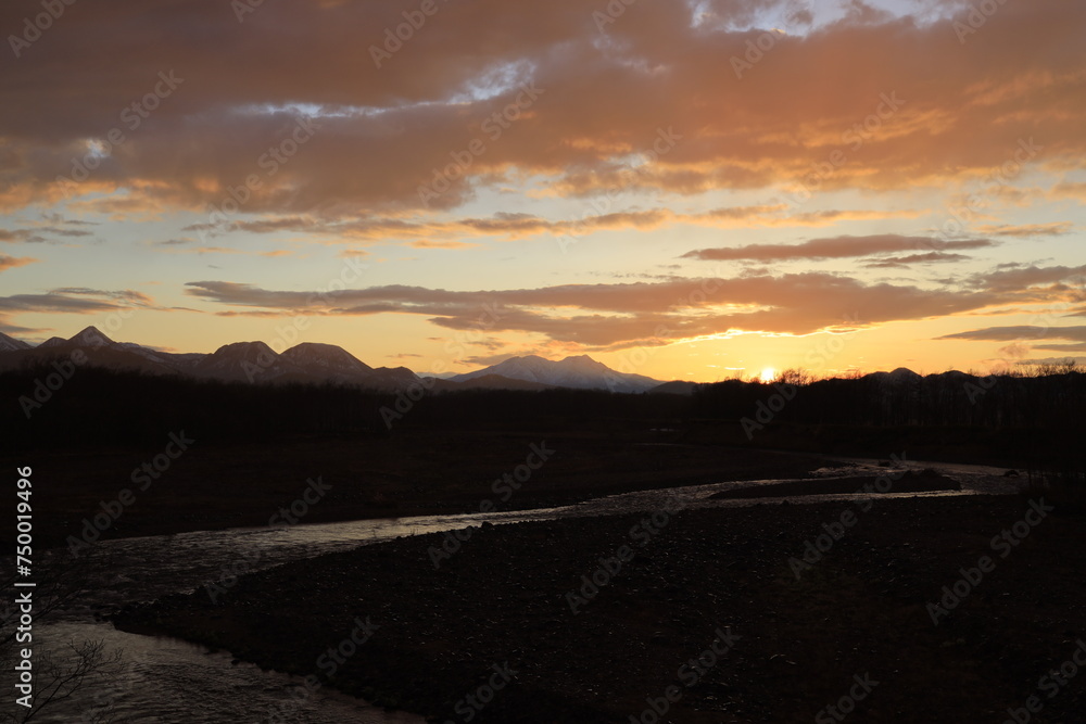 秋の始まりの北海道清流の忠類川斜里岳の向こうに夕陽が沈んで行きます 秋の始まりの北海道清流の忠類川斜里岳の向こうに夕陽が沈んで行きます