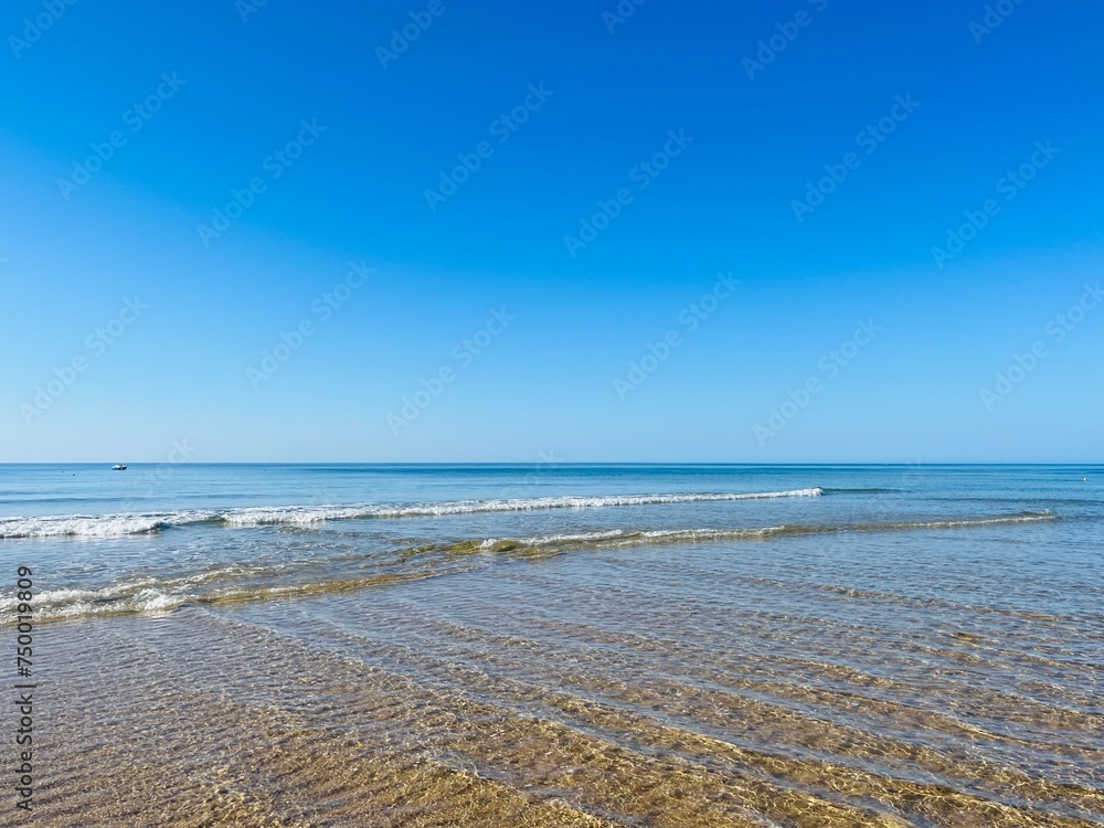 Obraz premium Transparent ocean water, ripples, sandy ocean coast, natural sea water background