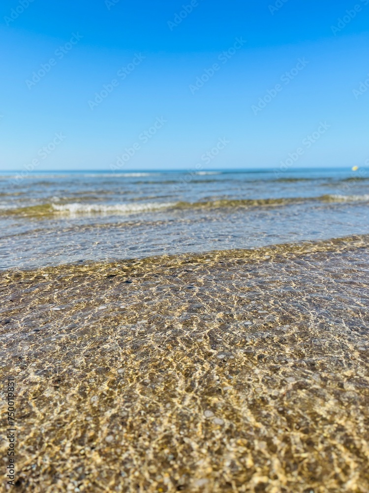 Transparent ocean water, ripples, sandy ocean coast, natural sea water background Transparent ocean water, ripples, sandy ocean coast, natural sea water background