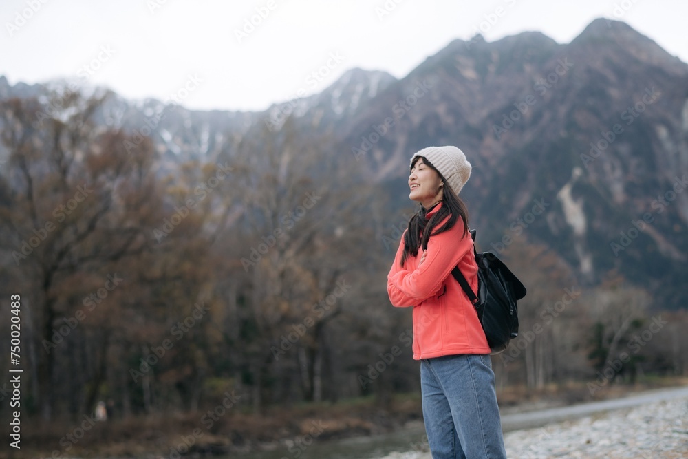 Scenic journey, Asian woman in a pink fleece explores Japan's destination. Alone by the lake, an elegant portrait capturing the achievement, happiness, and joy of a trip.