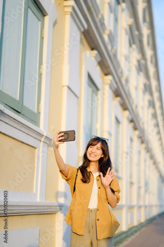 Traveler asian woman in her 30s making a livestream and sefie with a smartphone enjoying travel in Bangkok, Thailand. Journey trip lifestyle, world travel explorer or Asia summer tourism concept. © Jirawatfoto