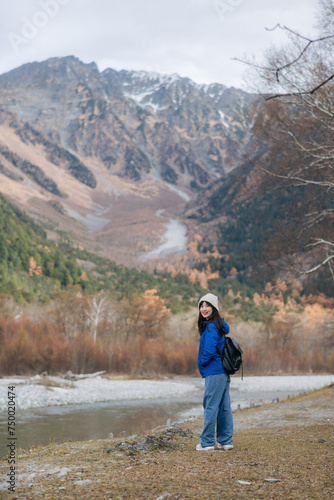 Cute traveler, Asian woman in a blue jacket stands by a cliff, enjoying the fall mood. A portrait of freedom and exploration in Japan's serene landscape.