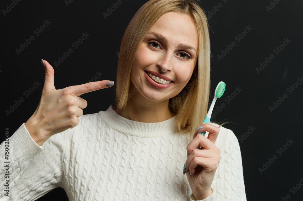 Obraz premium Young beautiful woman points her finger at the toothbrush.