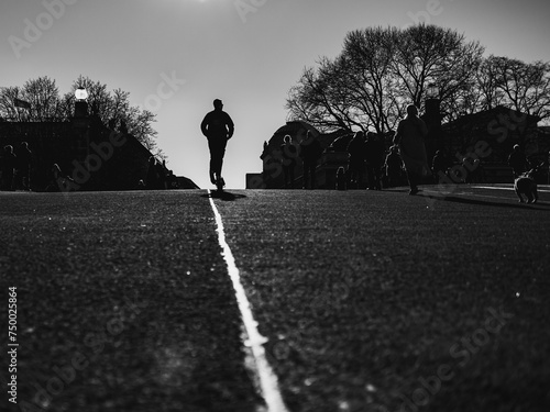 silhouette of a man on a scooter riding along an asphalt road