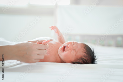 newborn male Is a person of Asian descent Lying in the bedroom on a white bed I'm crying. photo