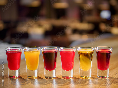 Set of colorful different bitters and liqueurs in shot glasses on bar counter. Collection of shooters. Selection of natural berry alcoholic tinctures in glasses. Different bitters and liqueurs © fascinadora