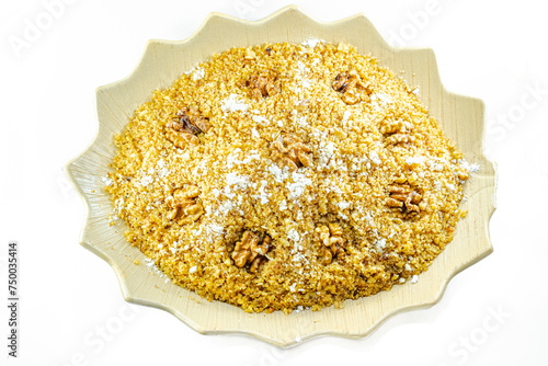 Rfiss, Algerian traditional semolina-based dessert, with dried fruit and whole nuts, sprinkled with powdered sugar. Served on a decorative plate, close-up overhead view isolated on a white background  photo