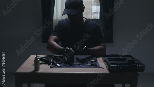 Slow motion image of a man sitting alone in a room. He would disassemble and clean a 9 mm semi-automatic pistol. assembling the gun. military ammunition. weapon care.