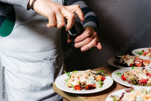 Foto Chef Seasoning Salad with Fresh Ground Pepper