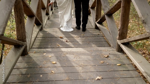 The newlyweds go down the steps. Taking the first step into family life. The feet of the bride and groom walk along the wooden steps. Bride and groom. © Ruslan
