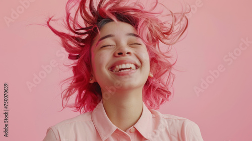 A person with pink hair and vibrant makeup is captured mid-motion with a look of blissful enjoyment, against a pink background.