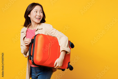 Traveler happy fun woman wear casual clothes hold suitcase bag look aside isolated on plain yellow background. Tourist travel abroad in free spare time rest getaway. Air flight trip journey concept.