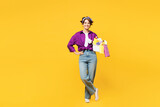 Full body young smiling happy woman wear casual purple shirt do housework tidy up hold basin with laundry clothes look camera isolated on plain yellow background studio portrait. Housekeeping concept.