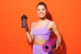 Young fun fitness trainer instructor sporty woman sportsman wear purple top clothes in home gym hold yoga mat drink protein cocktail isolated on plain orange background. Workout sport fit abs concept.