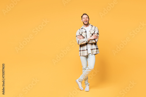 Full body smiling happy fun young Caucasian man he wear brown shirt casual clothes hold hands crossed folded look camera isolated on plain yellow orange background studio portrait. Lifestyle concept.